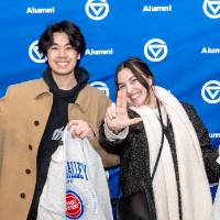 Two young people giving anchor up sign in front of photo backdrop